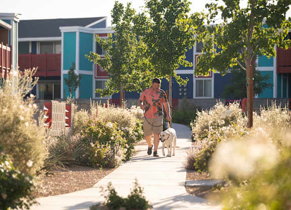 A man walking a dog on a path in a park.