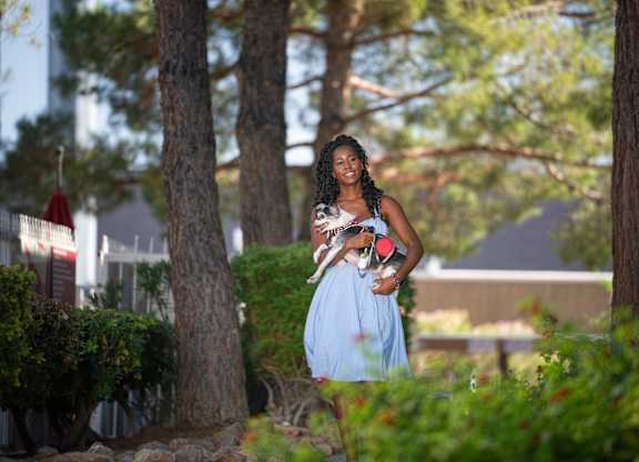 A woman in a blue dress is walking through a garden.