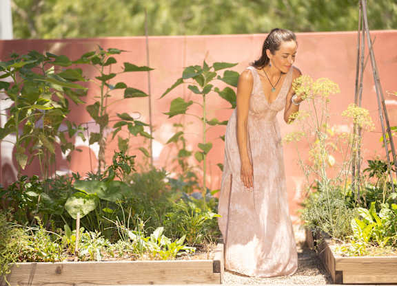 A woman in a white dress is standing in a garden.