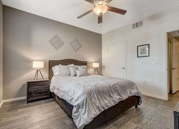 A bedroom with a bed, nightstand, and a ceiling fan.