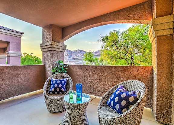A patio with two chairs and a table with a blue pillow on it.