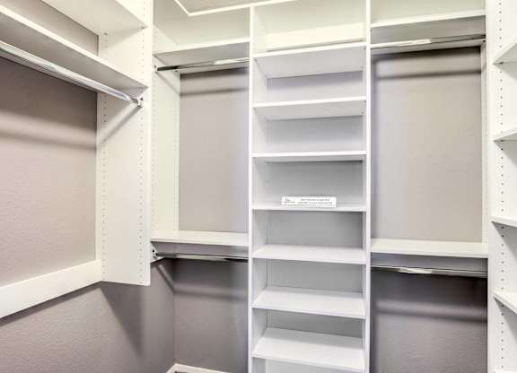 A white pantry with shelves and a grey door.