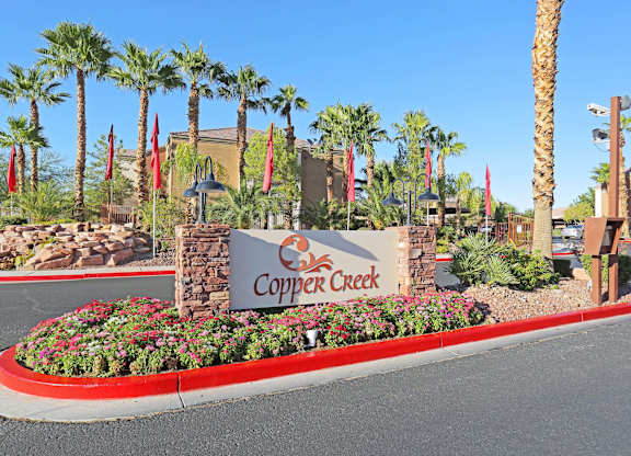 A sign for Copper Creek is in front of some palm trees.