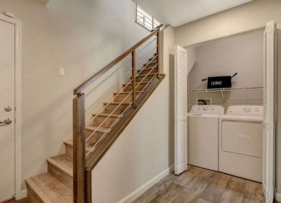 A staircase with a wooden handrail leads to a laundry room with a washer and dryer. at Habitat @ DTLV, Las Vegas