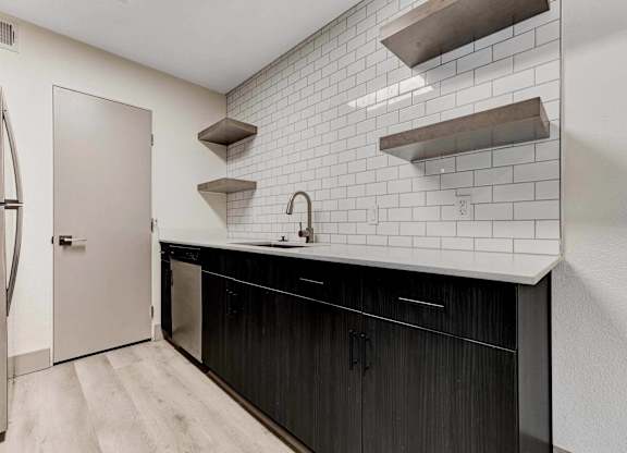 A kitchen with black cabinets and white subway tiles.