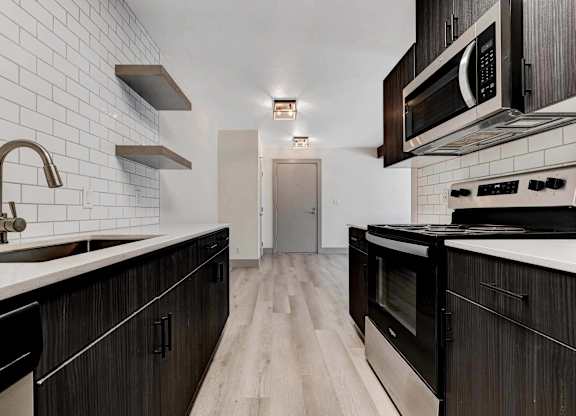 A kitchen with black cabinets and a white tiled backsplash.