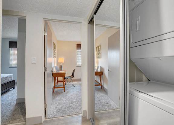 A white refrigerator is in the kitchen area of a small apartment.