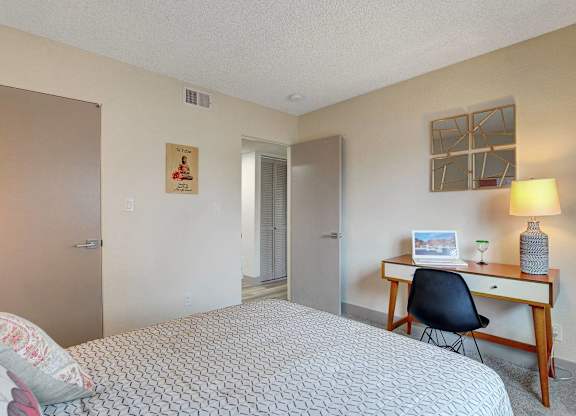 A bedroom with a bed, desk, and chair.