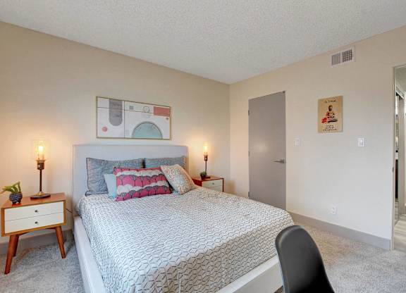 A bedroom with a bed, a chair, and a painting on the wall.