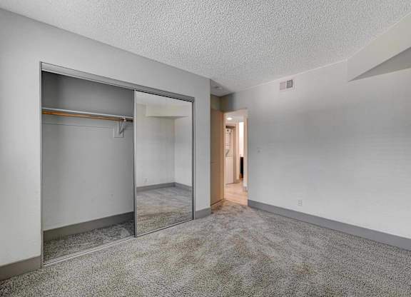 A room with a white wall and a grey carpet.