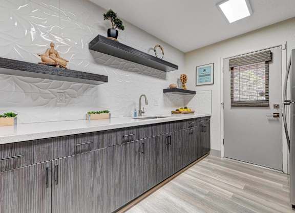 A kitchen with a white counter top and grey cabinets.