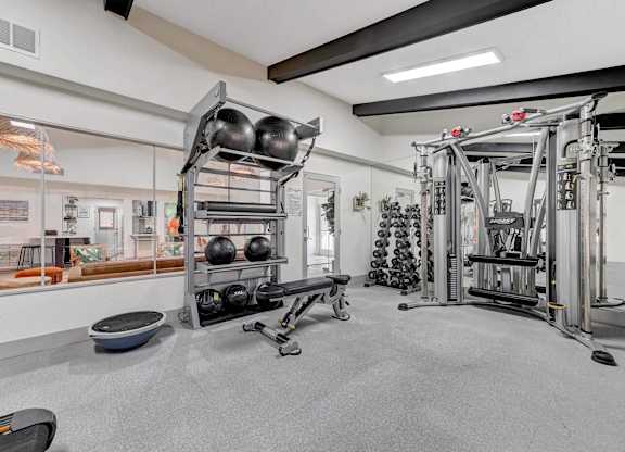 A gym with a variety of equipment including weights and a rowing machine.