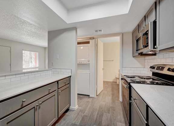 A kitchen with white countertops and stainless steel appliances.