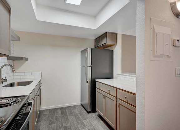 A kitchen with a stainless steel refrigerator and wooden cabinets.