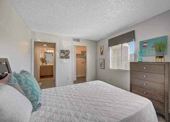 A bedroom with a bed, dresser, and a painting on the wall.