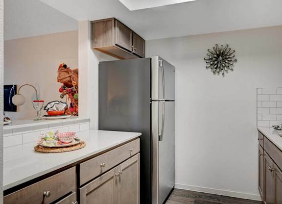 A kitchen with a refrigerator, countertop, and cabinets.