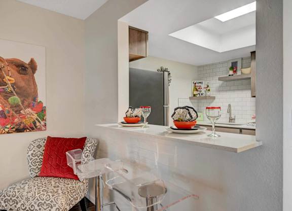 A kitchen with a white counter and a painting of a camel on the wall.