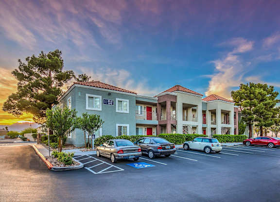 A parking lot in front of a building with cars parked.