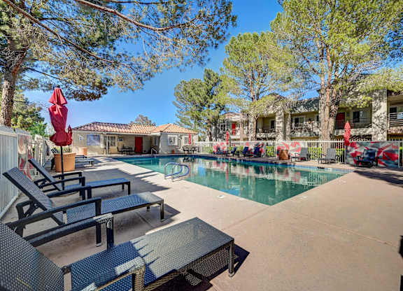 A pool area with lounge chairs and umbrellas.