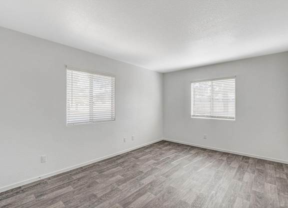A room with wooden flooring and two windows with blinds. at The 95 Apartments, Las Vegas, 89129