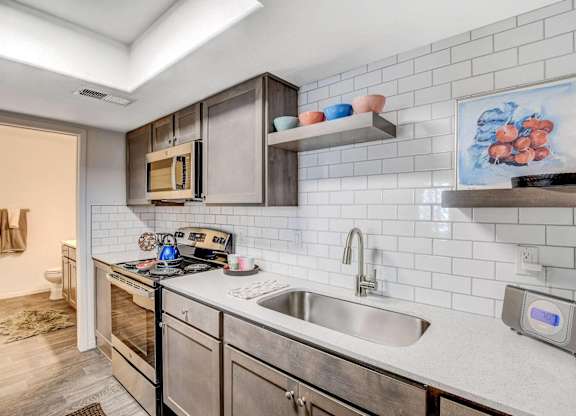 A modern kitchen with stainless steel appliances and a white tiled backsplash. at The 95 Apartments, Las Vegas, Nevada