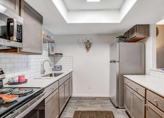 A kitchen with a stove top oven, microwave, and refrigerator. at The 95 Apartments, Las Vegas, NV, 89129