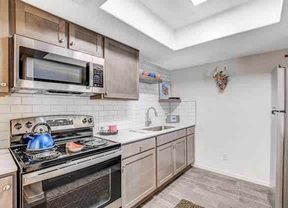A kitchen with a stove, microwave, and refrigerator. at The 95 Apartments, Las Vegas