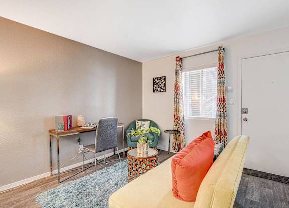 A room with a yellow couch and a desk with a chair. at The 95 Apartments, Nevada