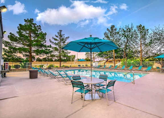 A poolside area with chairs and umbrellas. at The 95 Apartments, Las Vegas, NV, 89129