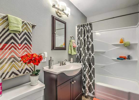 A bathroom with a white tub and a sink with a mirror above it.