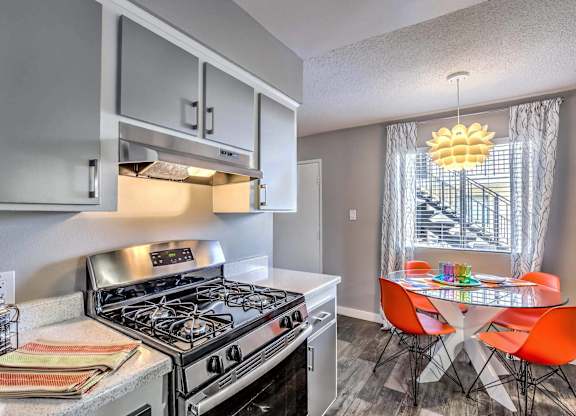 A modern kitchen with a stove top oven and a dining table with chairs.