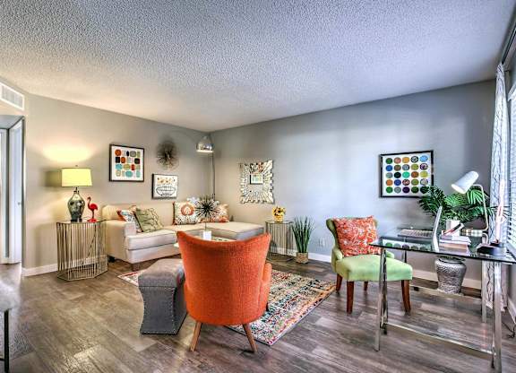 A living room with a white couch, a red chair, and a green chair.