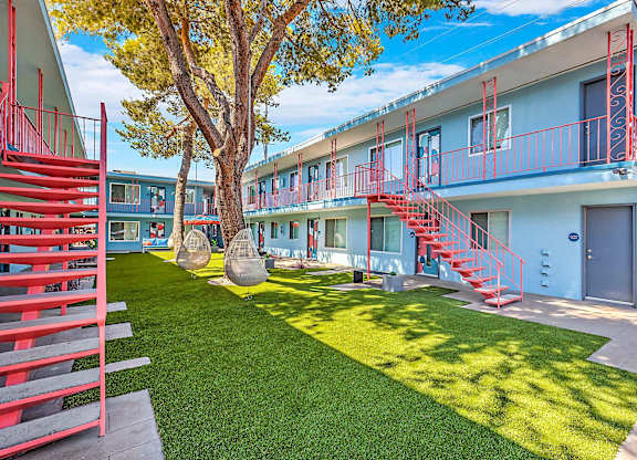A tree in a courtyard with a red staircase.