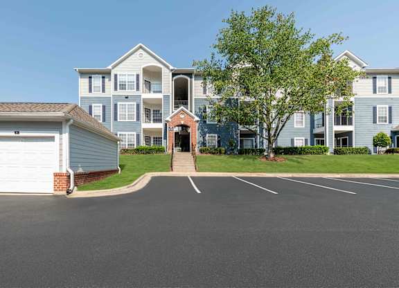A large apartment complex with a parking lot in front.
