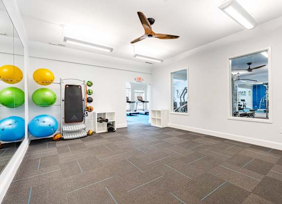 A room with a treadmill, exercise balls, and a mirror.