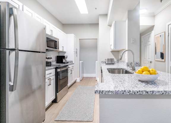 A modern kitchen with a refrigerator, sink, and countertop.