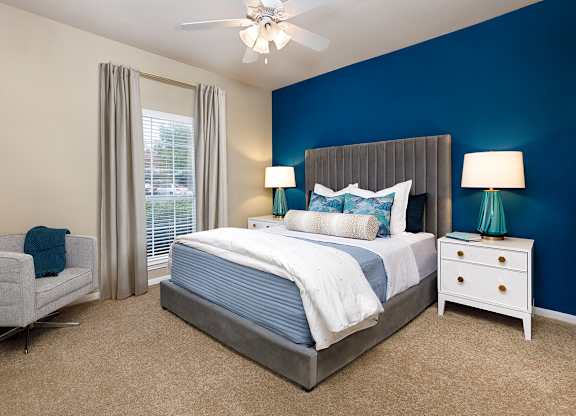 A bedroom with a bed, nightstand, and chair.