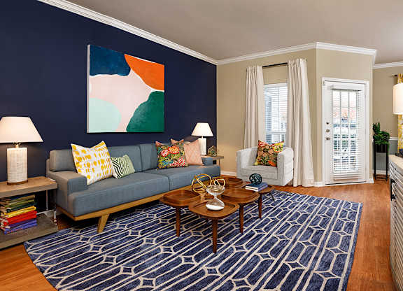 A living room with a blue couch and a painting on the wall.