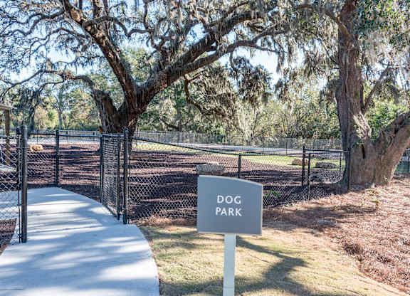 A sign that says Dog Park stands in front of a fence.