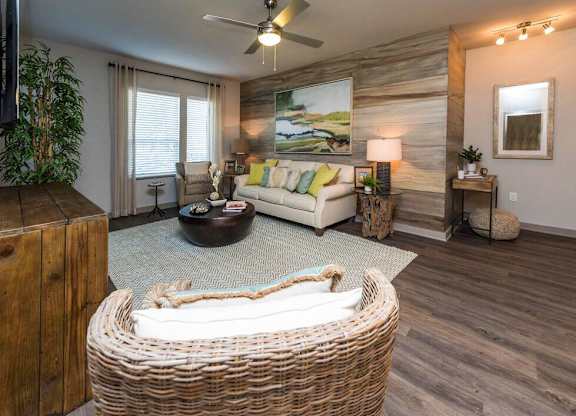 A living room with a wicker sofa and a painting on the wall.