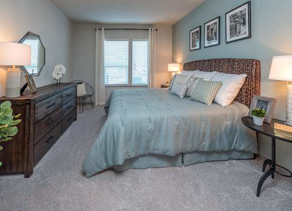 A bedroom with a bed, nightstands, and a dresser.