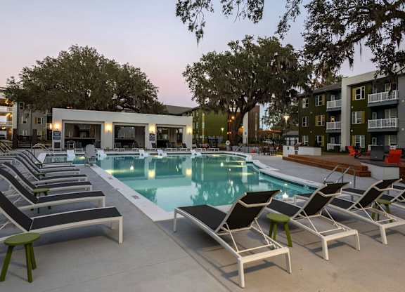 A poolside area with lounge chairs and a building in the background.