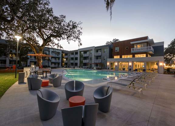 A modern outdoor pool area with lounge chairs and a building in the background.