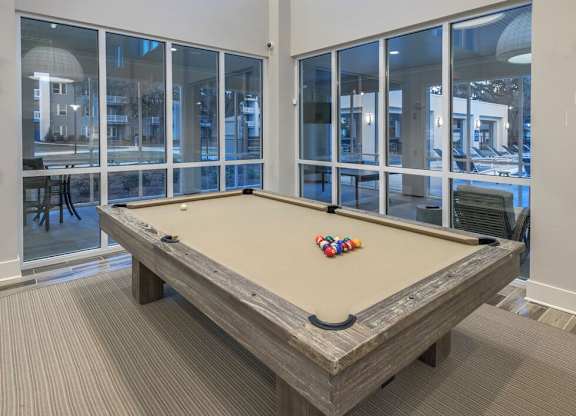 A pool table in a room with a view of the outside.