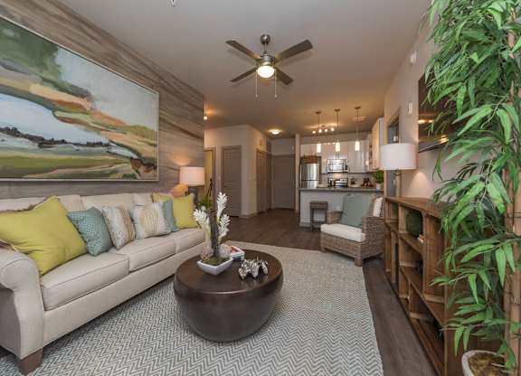 A living room with a large painting on the wall and a couch with yellow pillows.