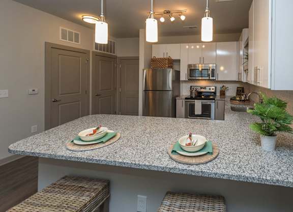 A kitchen with granite countertops and a stainless steel refrigerator.