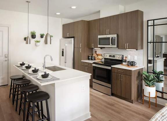 A modern kitchen with a white island and dark wood cabinets.