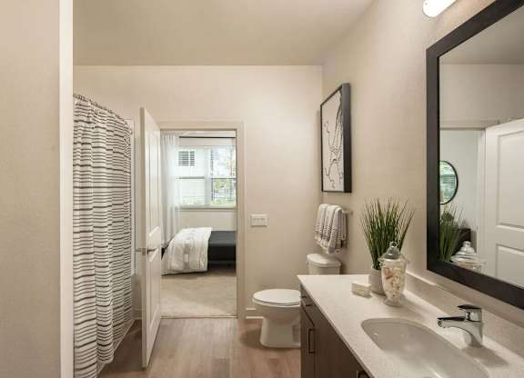 A bathroom with a toilet, sink, and mirror.