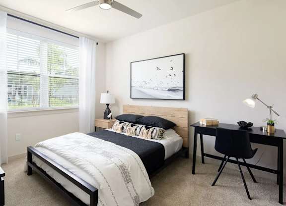 A bedroom with a bed, desk, and chair.