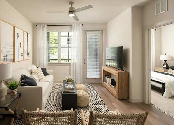A living room with a white couch, a glass coffee table, and a television.